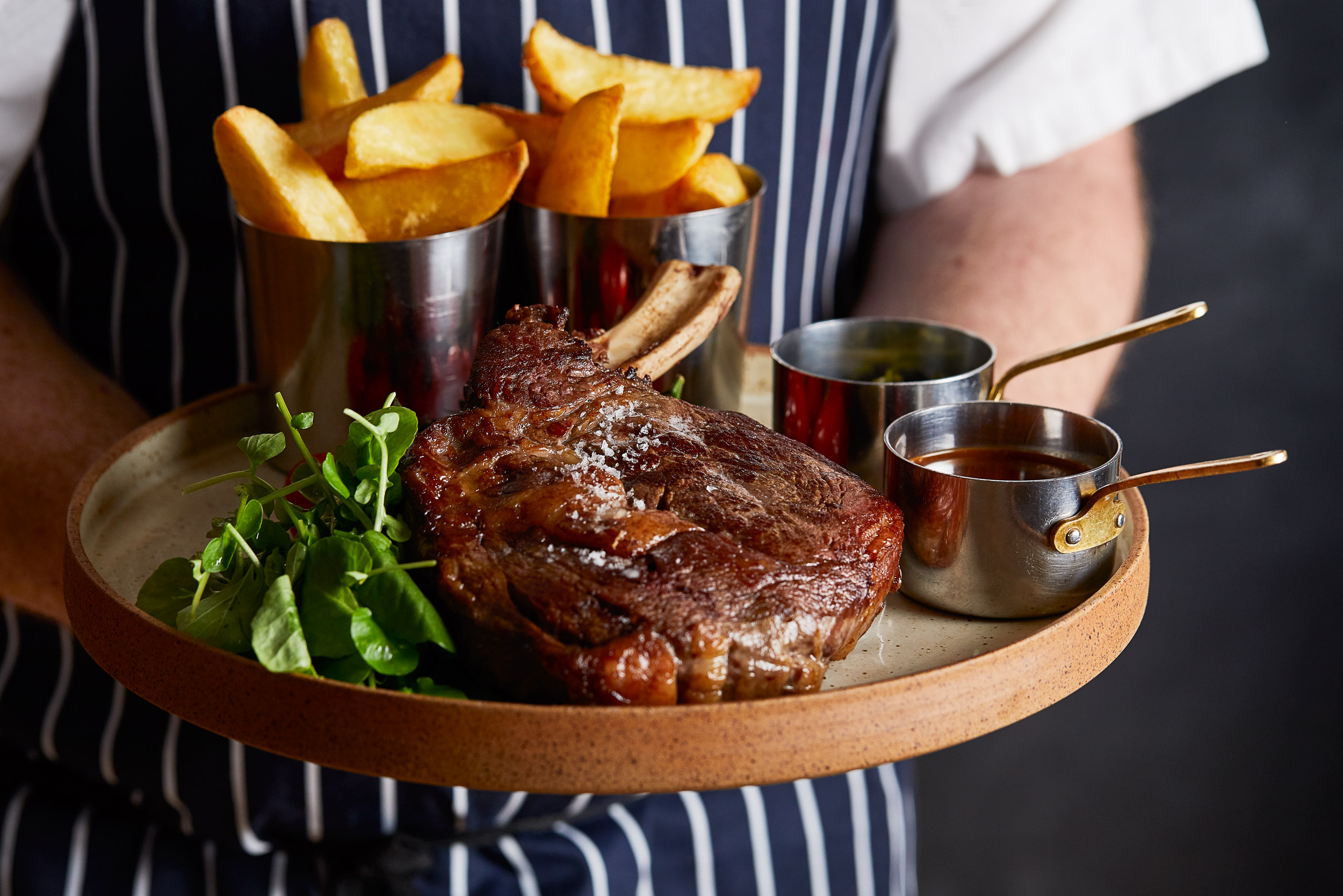 Chef holding a plate of Rib of Beef and Chips. Alastair Ferrier food and drink photographer, Edinburgh.